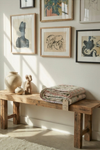 Wooden bench with decorative items against a wall with framed art