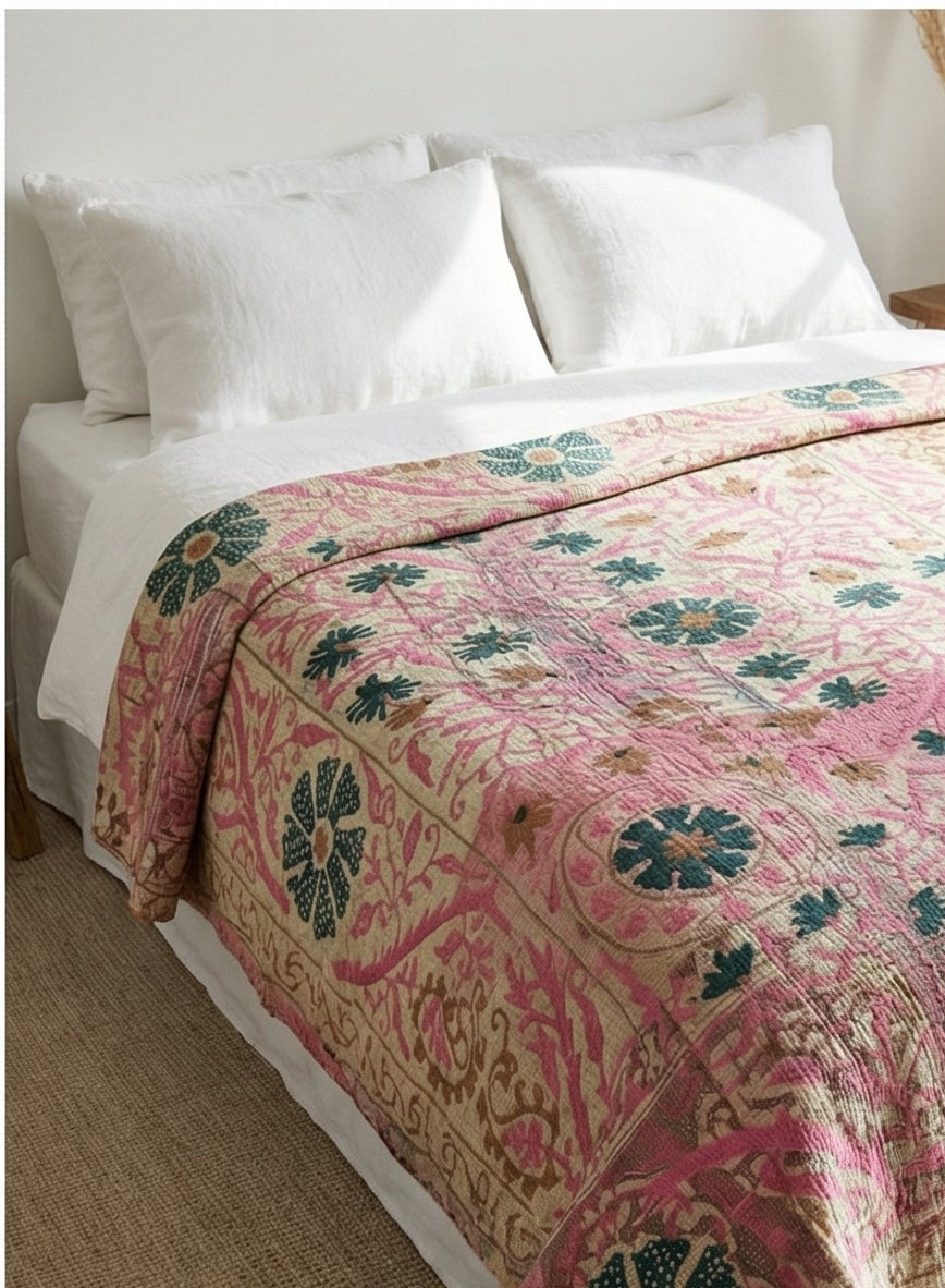 Bed with a floral patterned quilt on a white bedspread