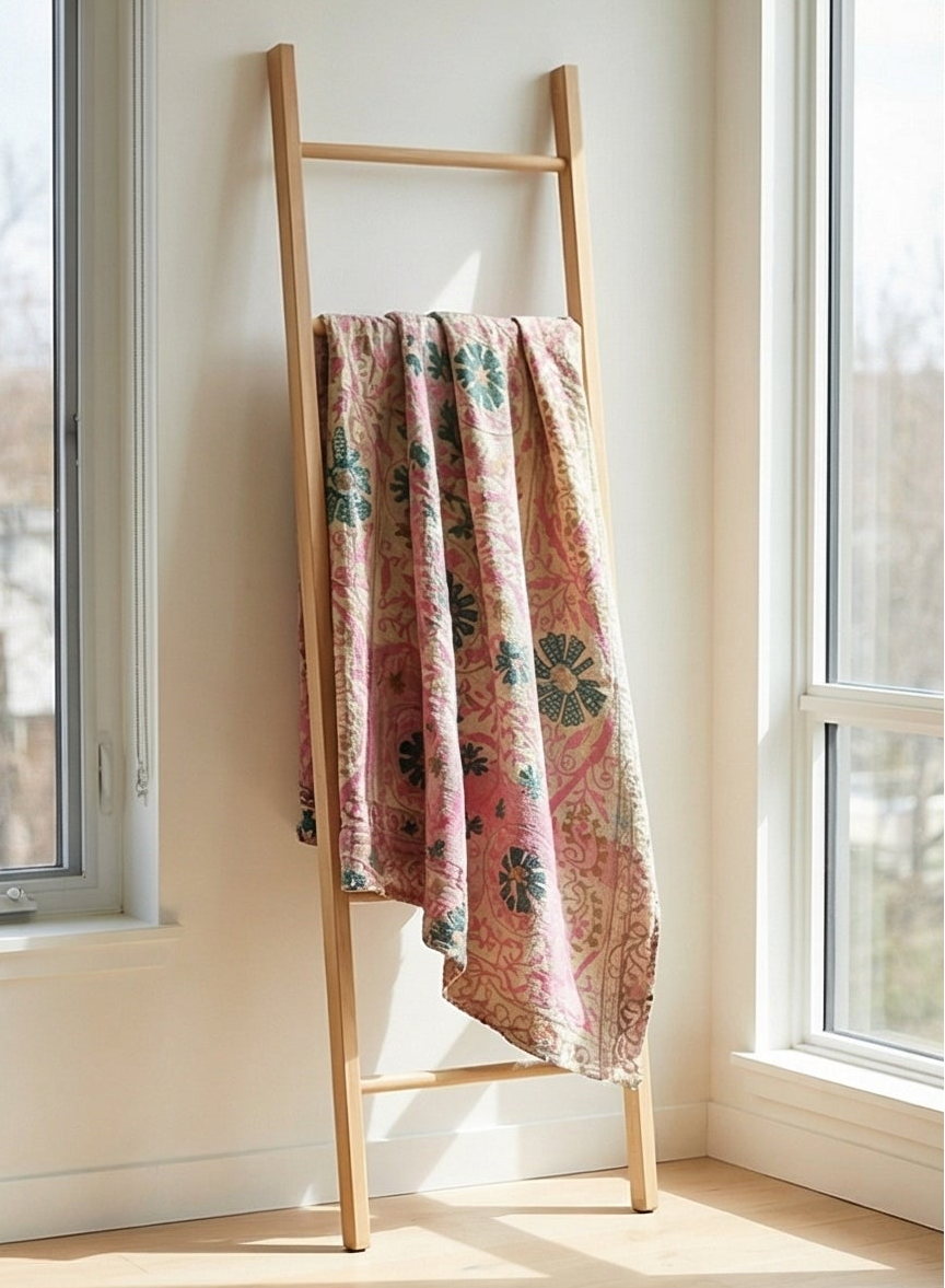 Wooden ladder with a floral-patterned towel against a light wall.