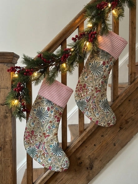Decorative stockings on a staircase, table, and window seat with a snowy view.