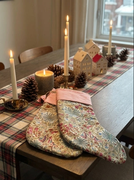 Decorative stockings on a staircase, table, and window seat with a snowy view.