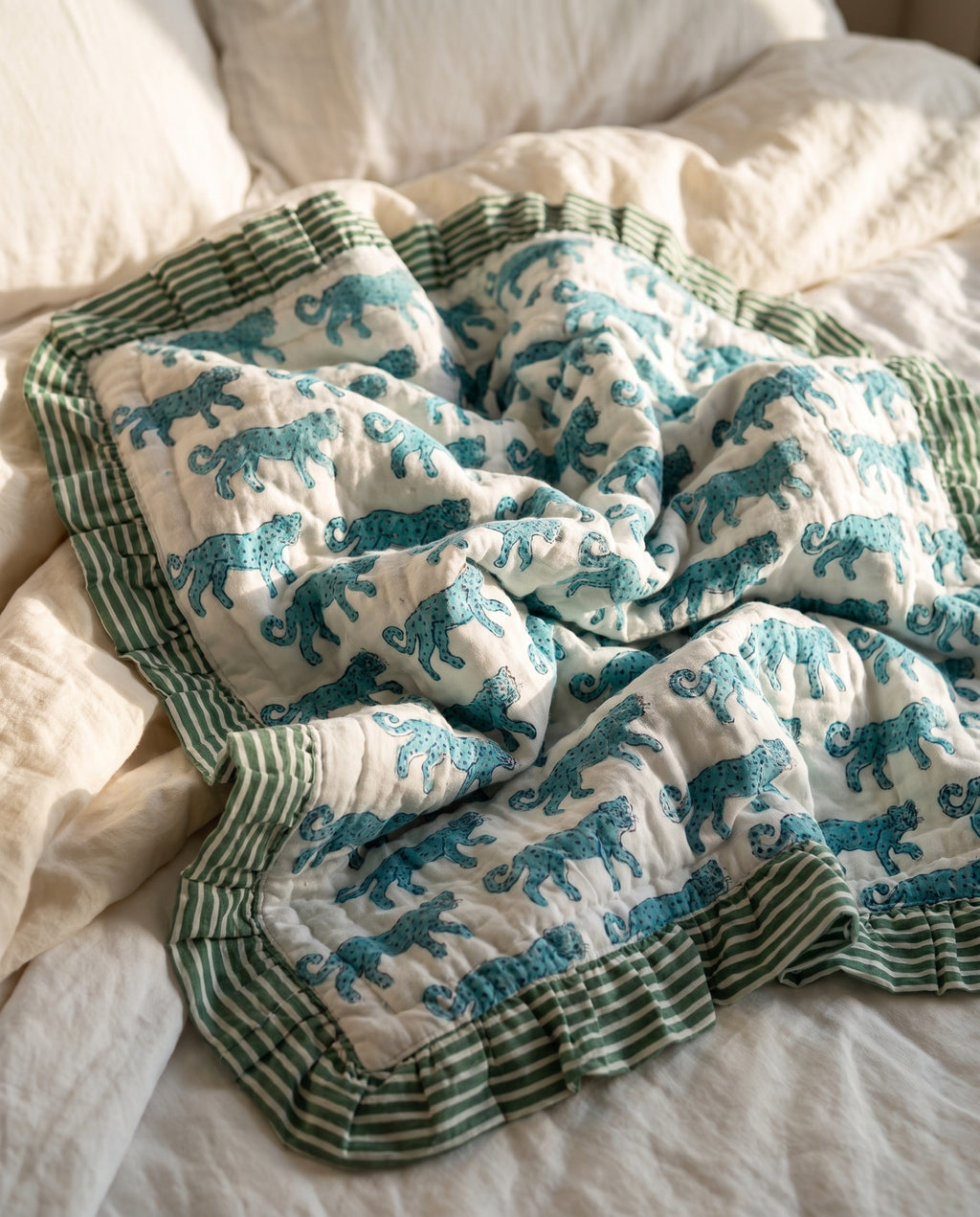 Elephant Meadow reversible cotton baby blanket, side one, bed editorial