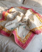 Flamingo Daydreams reversible cotton baby blanket, side one, bed editorial