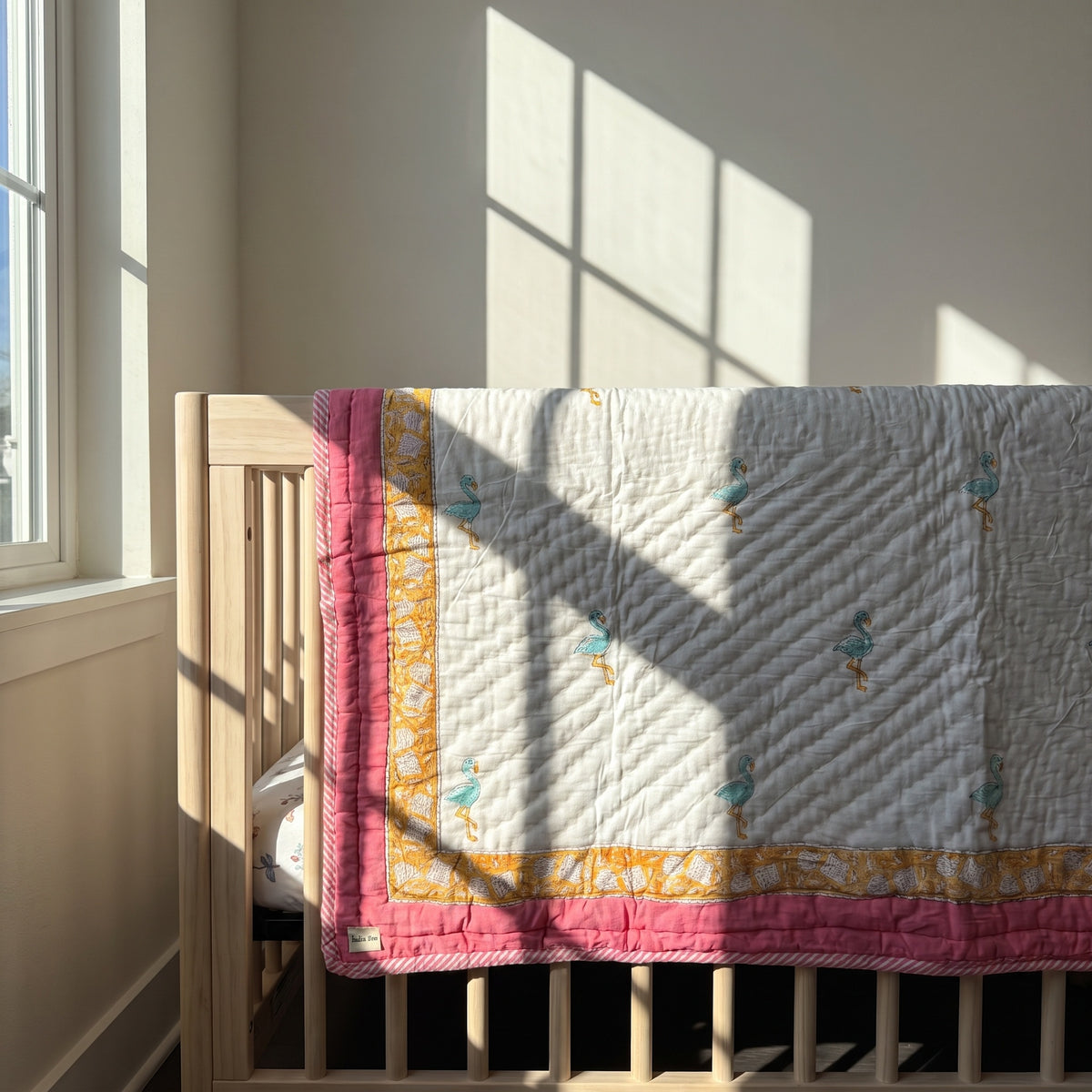 Flamingo Daydreams reversible cotton baby blanket, side one, crib rail