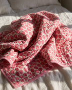 Berry Picnic reversible cotton baby blanket, side one, bed editorial