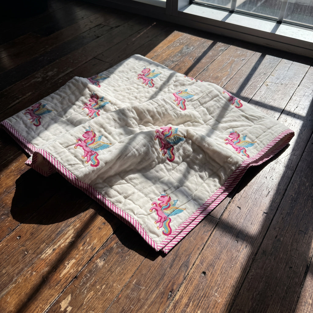 Unicorn Wishes reversible cotton baby blanket, side one, floor
