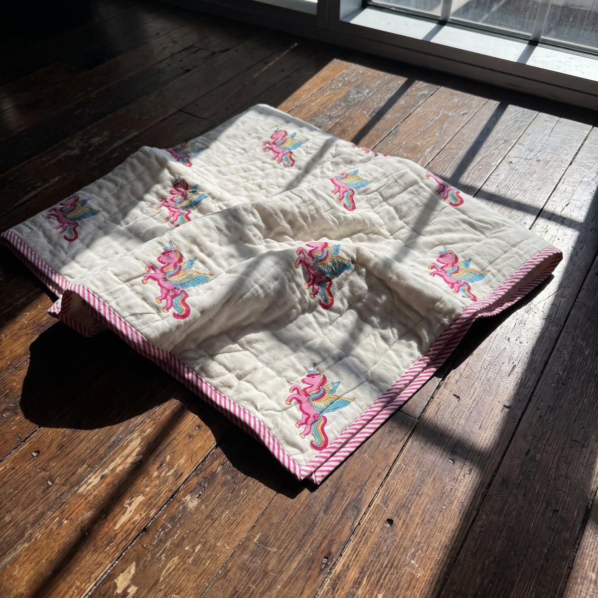 Unicorn Wishes reversible cotton baby blanket, side one, floor