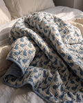 Bunny Trails reversible cotton baby blanket, side one, bed editorial
