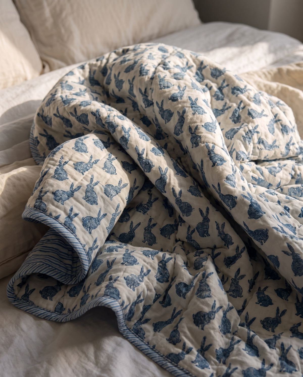 Bunny Trails reversible cotton baby blanket, side one, bed editorial