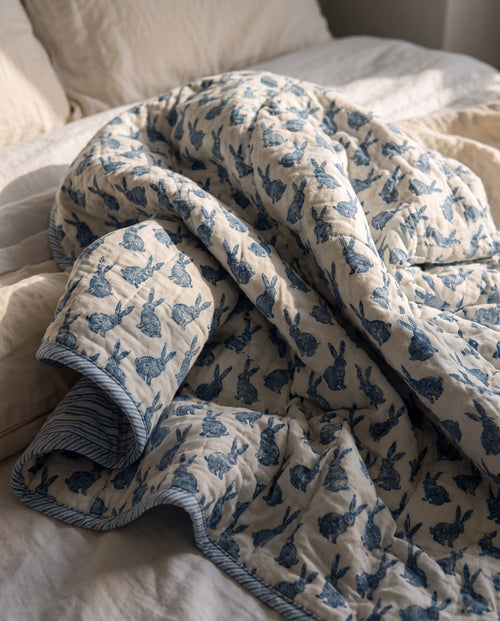 Bunny Trails reversible cotton baby blanket, side one, bed editorial