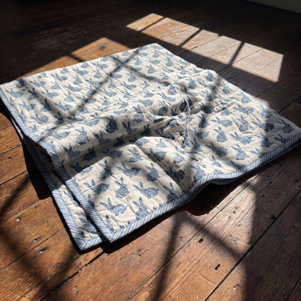 Bunny Trails reversible cotton baby blanket, side one, floor