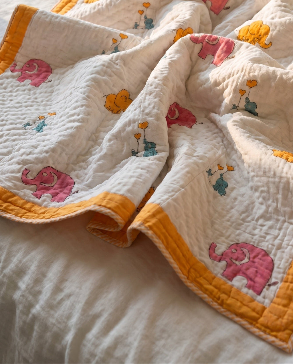 Elephant Wishes reversible cotton baby blanket, side one, bed editorial