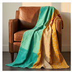 Colorful blanket draped over a brown leather armchair in a room.