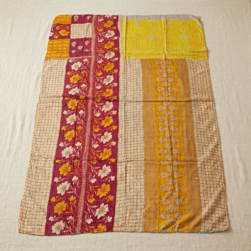 Colorful quilt with floral and geometric patterns on a beige background