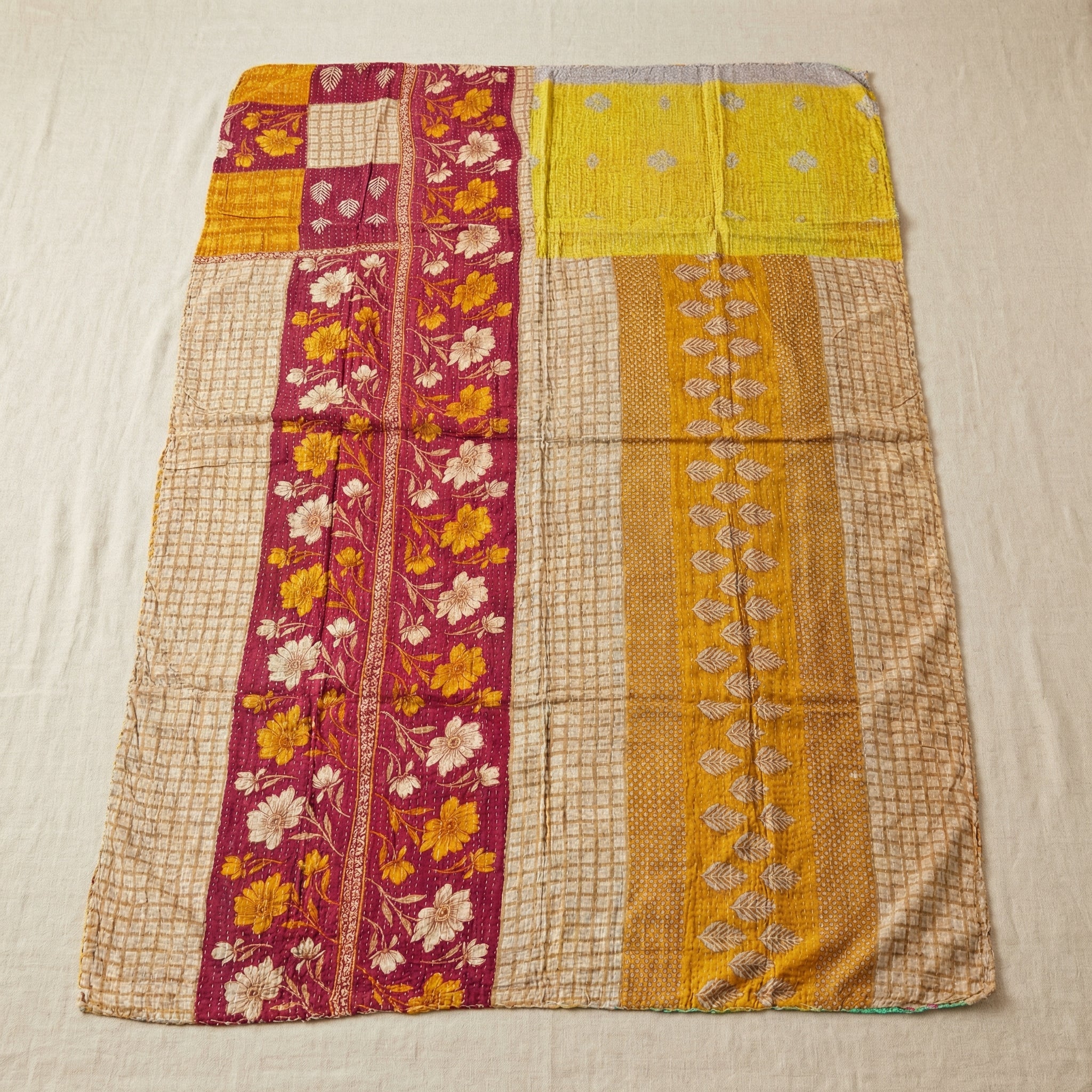 Colorful quilt with floral and geometric patterns on a beige background