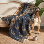 A Wanderer's Loom Vintage Cotton Kantha Throw in navy blue is adorned with intricate gold ornate scrollwork, paisley motifs, and geometric borders, featuring cream dashed line stitching and a light beige reverse side.