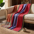 The Nomad Story Vintage Cotton Kantha Throw features dominant red, blue, and orange panels, showcasing characteristic Kantha grid stitching, a subtle dotted pattern, and an elaborate floral and paisley border, highlighted with olive green and black striped accents.