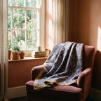 Prairie Crocus Bagru Kantha Throw — front draped over a chair in a cosy reading nook