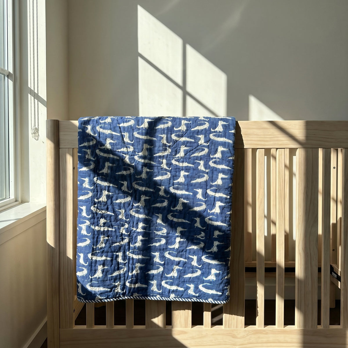 This Bubbles and Giggles (Big) - 100% cotton, Reversible Hand Made Artisnal Baby Quilt features a dark blue background with off-white stylized alligator motifs and a white and dark blue striped border.